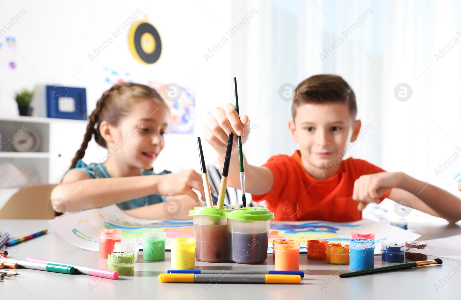 Photo of Little children painting picture at table indoors