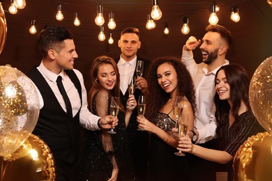 Photo of Happy friends with glasses of sparkling wine celebrating New Year indoors