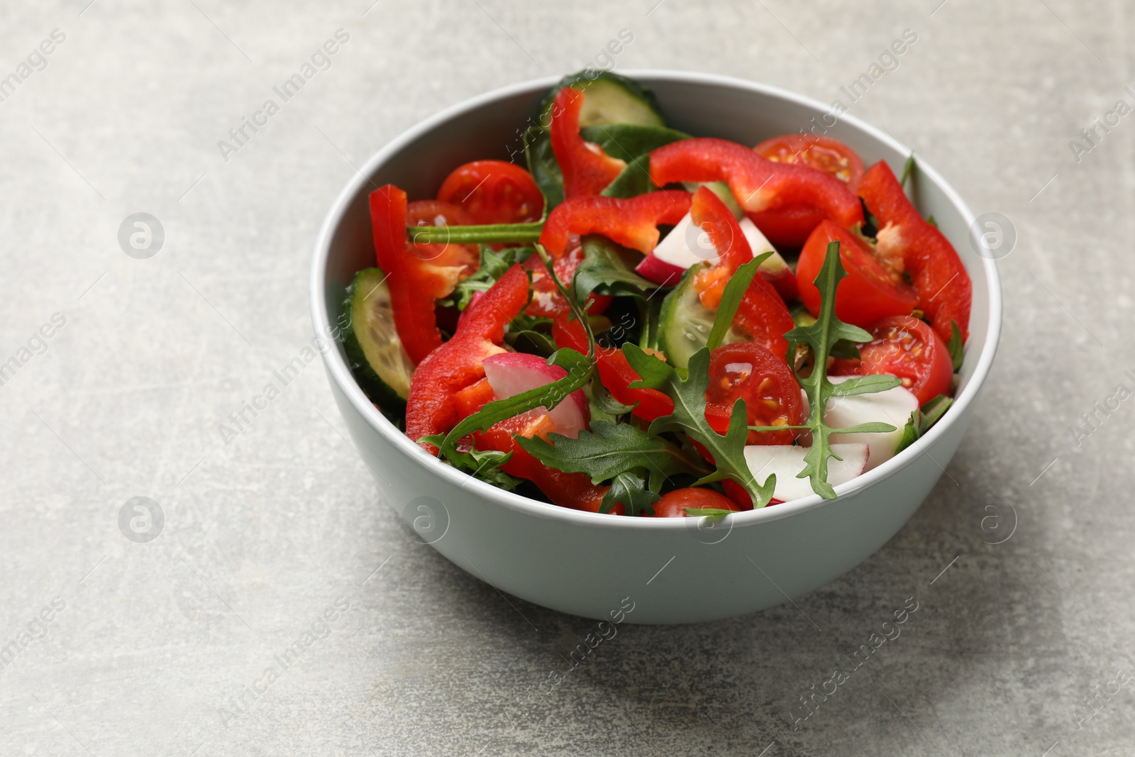 Photo of Tasty fresh vegetarian salad on light grey table