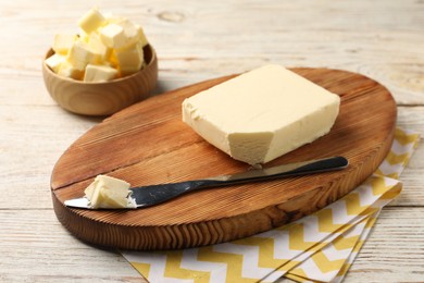 Photo of Tasty butter and knife on light wooden table