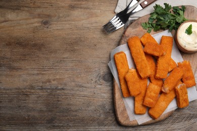 Photo of Tasty fresh fish fingers served on wooden table, flat lay. Space for text