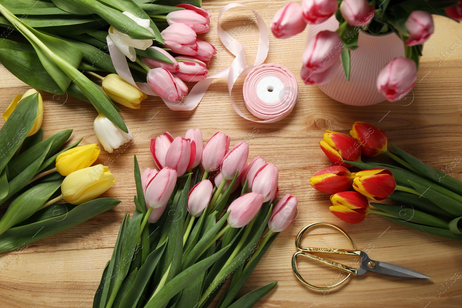 Photo of Making beautiful bouquet. Fresh tulips, ribbon and scissors on wooden table, flat lay