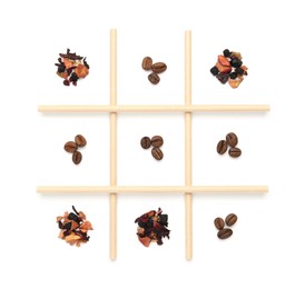 Photo of Tic tac toe game made with coffee beans and dry tea leaves isolated on white, top view