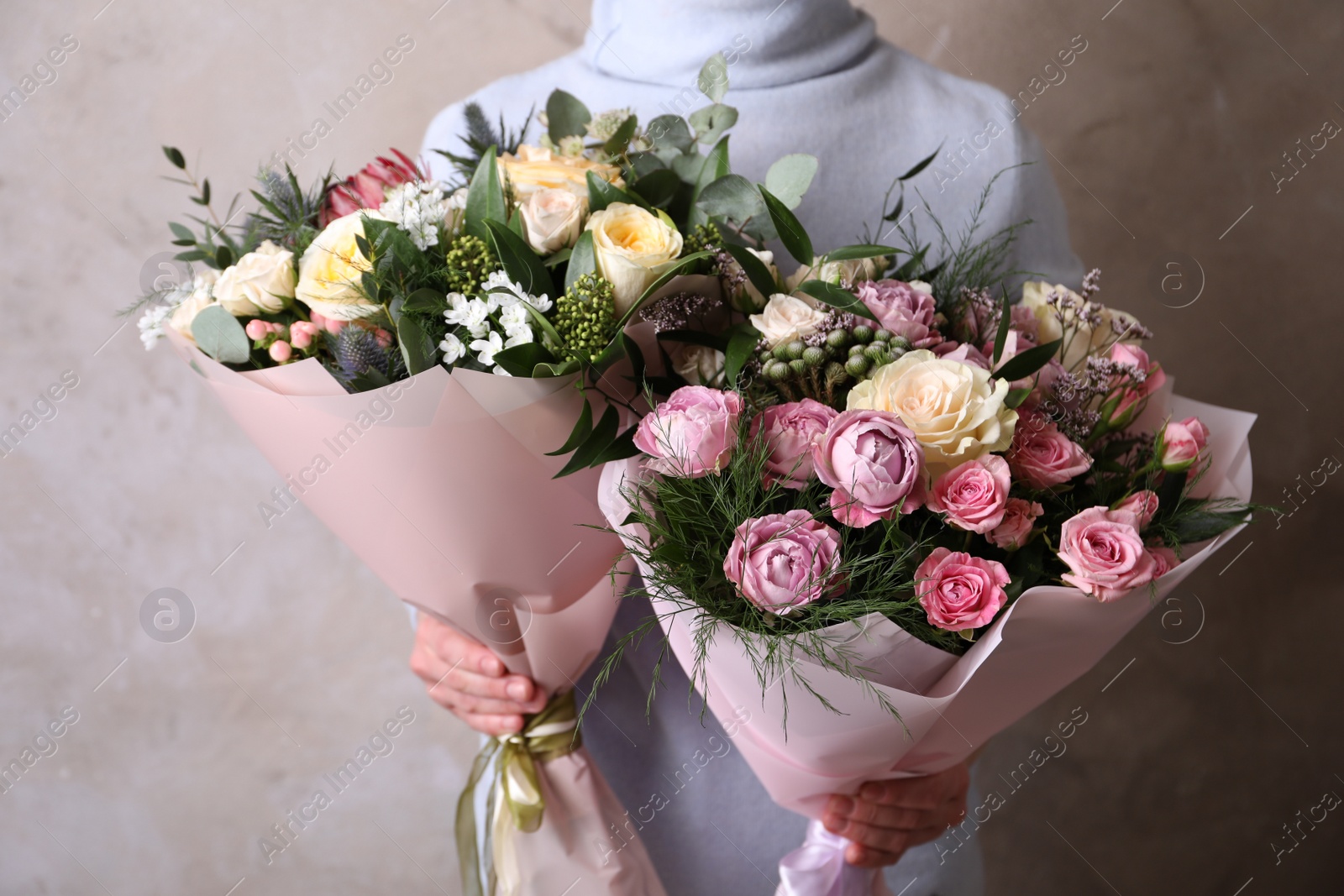 Photo of Woman with bouquets of beautiful flowers on beige background, closeup