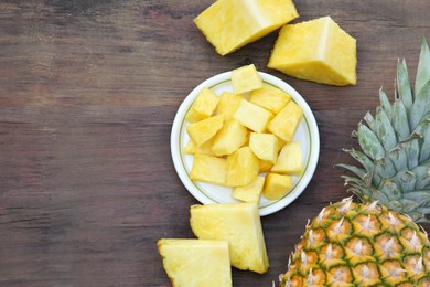 Photo of Cut and whole ripe pineapples on wooden table, flat lay. Space for text