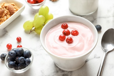 Photo of Bowl with tasty yogurt and berries on table