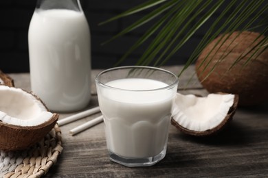 Glass of delicious vegan milk and coconuts on wooden table