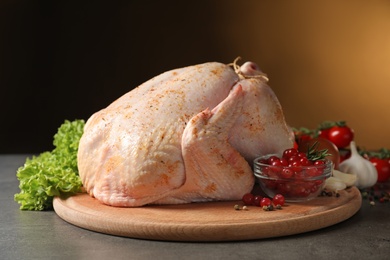 Photo of Wooden board with raw spiced turkey and ingredients on table