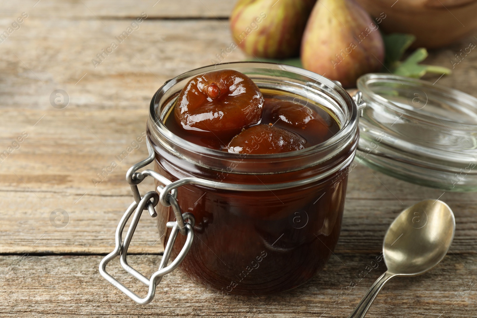 Photo of Jar of tasty sweet fig jam on wooden table