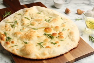 Delicious focaccia bread on wooden board, closeup