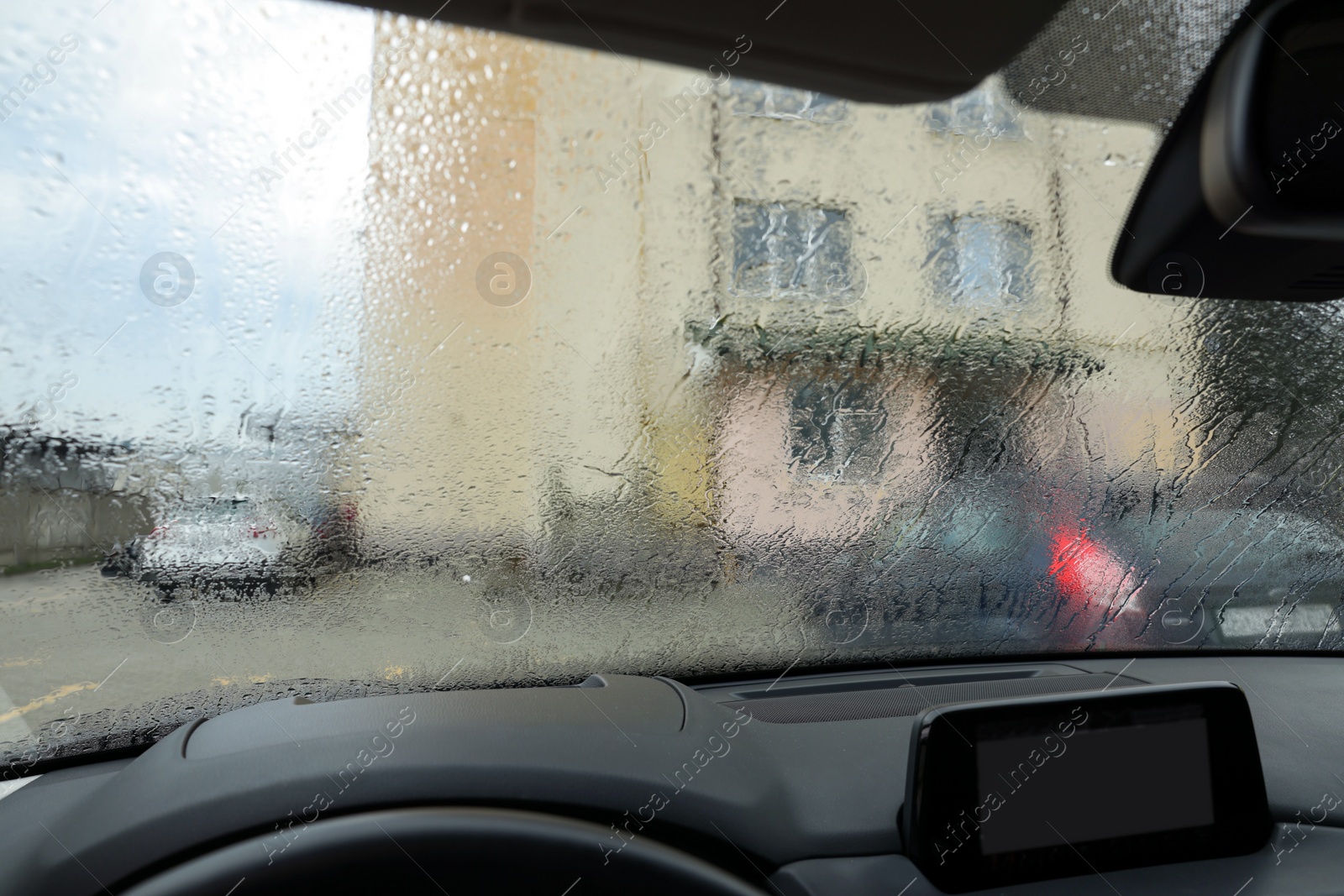 Photo of View on street from modern car windshield with rain drops, closeup
