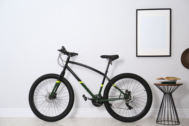 Photo of Modern black bicycle near light wall indoors