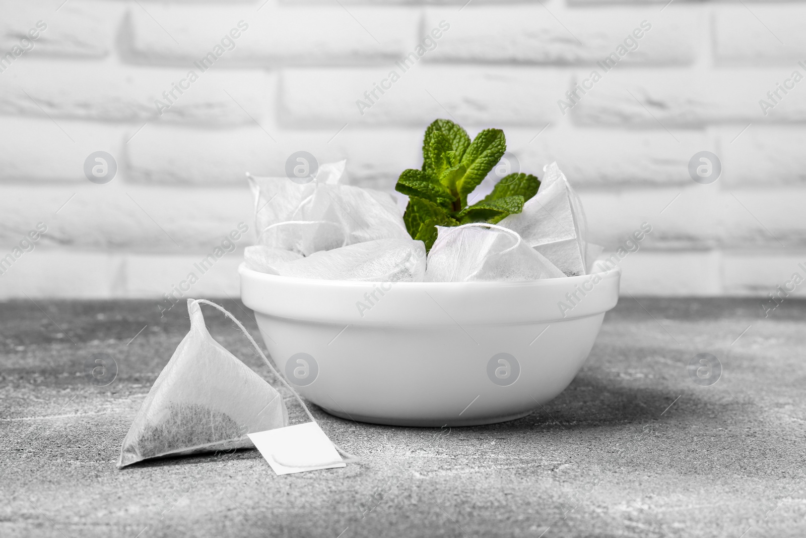 Photo of Tea bags and mint on light grey table, closeup