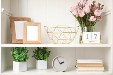 Photo of White shelving unit with plants and different decorative stuff