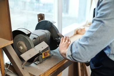 Working man using grinding machine at carpentry shop, closeup