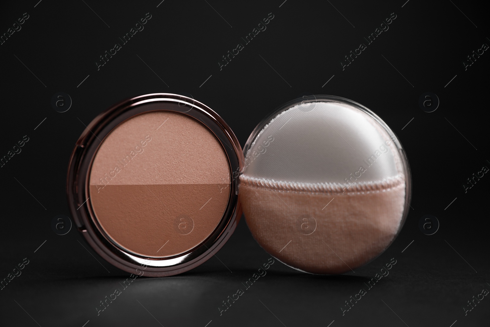 Photo of Open face powder with puff applicator on black background, closeup