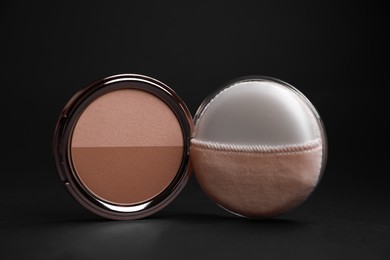 Photo of Open face powder with puff applicator on black background, closeup