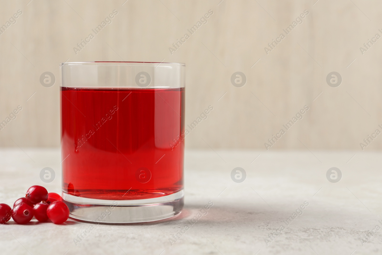 Photo of Tasty refreshing cranberry juice and fresh berries on light table. Space for text