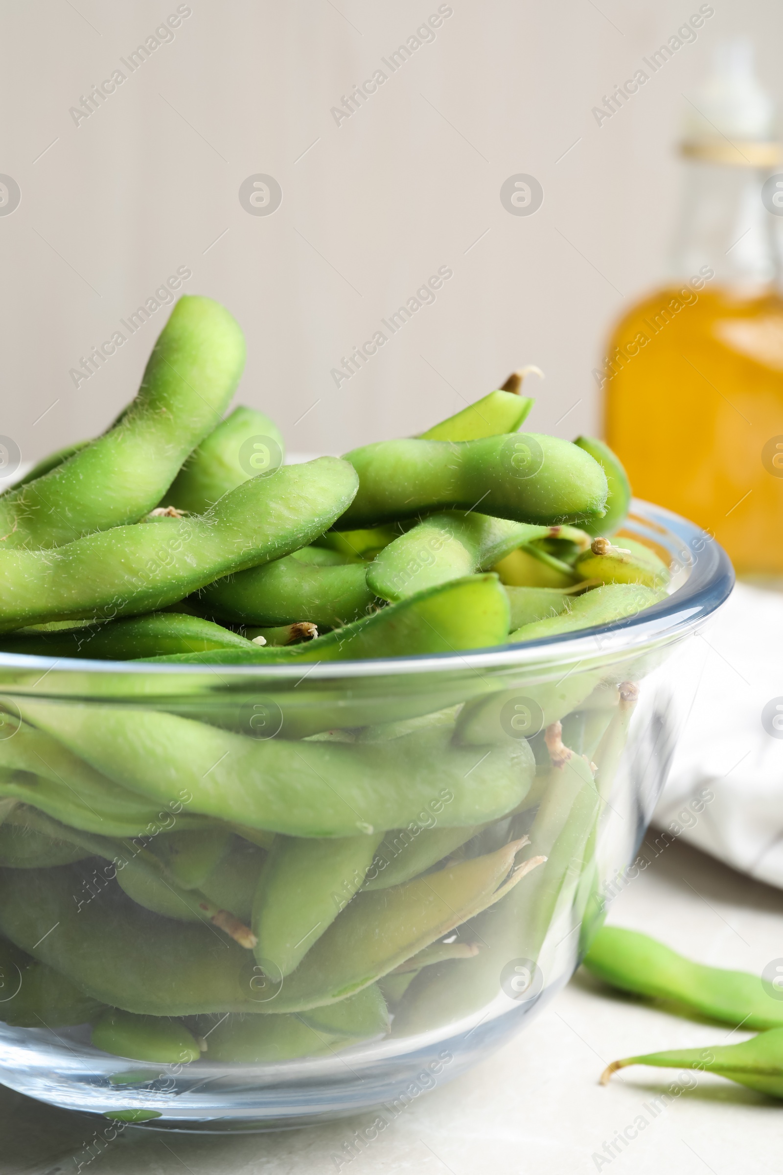 Photo of Bowl with green edamame beans in pods on light grey table