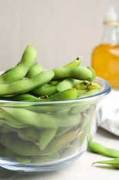 Bowl with green edamame beans in pods on light grey table