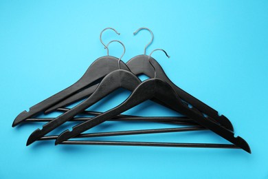 Photo of Black hangers on light blue background, top view