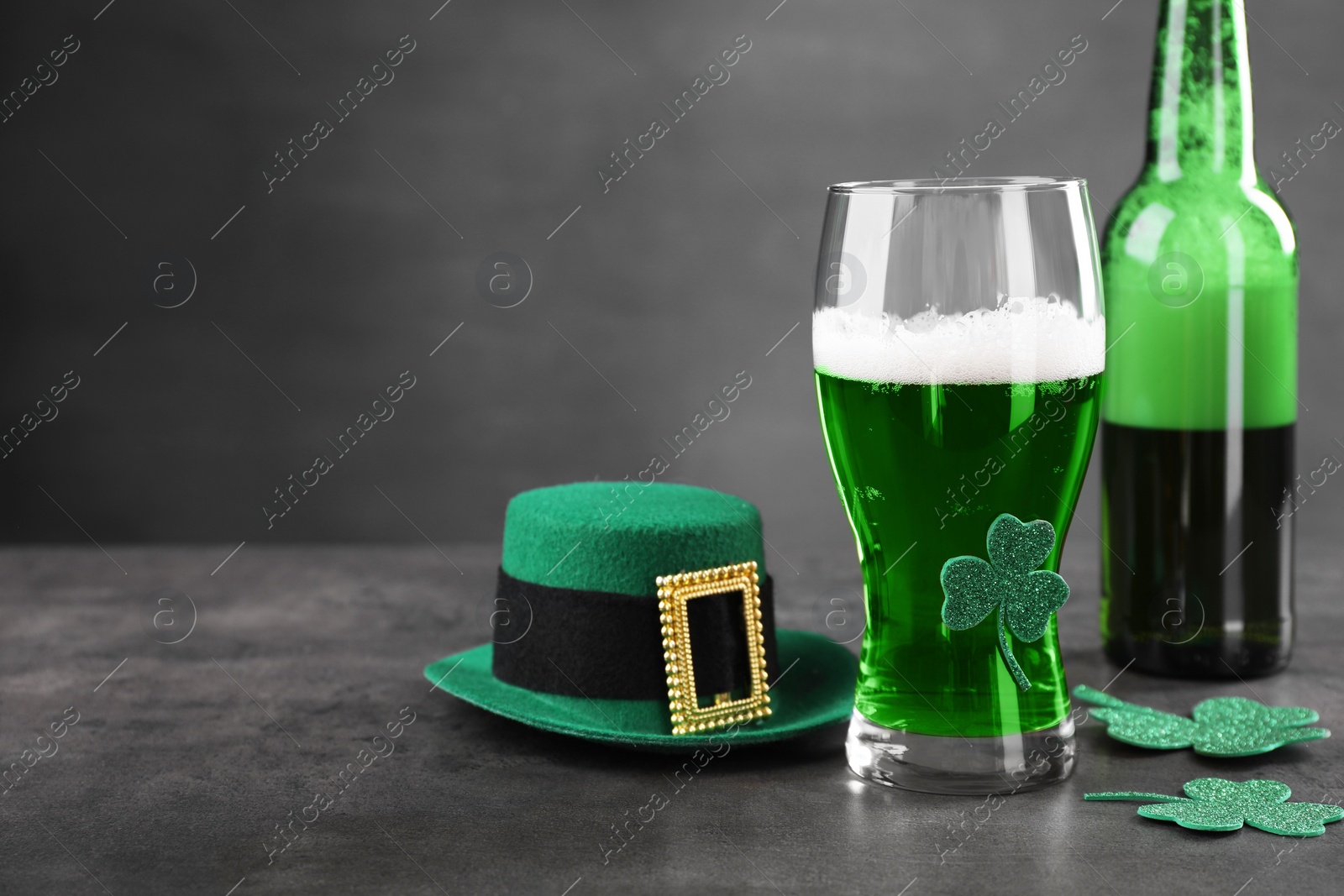 Photo of St. Patrick's day celebration. Green beer, leprechaun hat and decorative clover leaves on grey table. Space for text