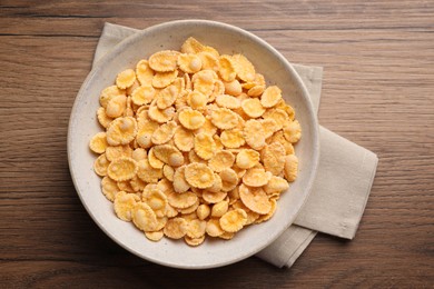 Photo of Bowl of tasty corn flakes on wooden table, top view