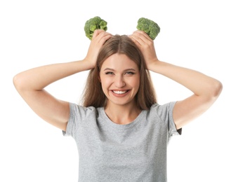 Portrait of funny woman holding broccoli as horns on white background