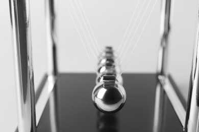 Photo of Newton's cradle on light background, closeup. Physics law of energy conservation
