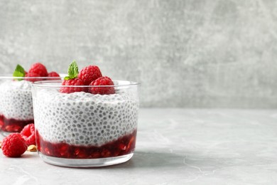 Delicious chia pudding with raspberries and mint on light marble table, space for text