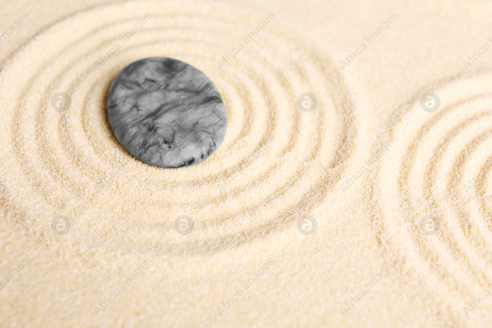 Photo of Zen garden stones on beige sand with pattern