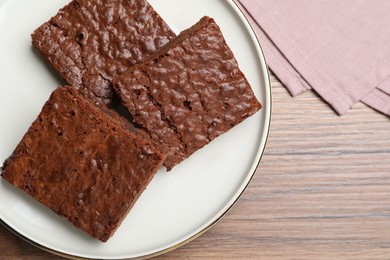 Photo of Delicious chocolate brownies on wooden table, top view. Space for text