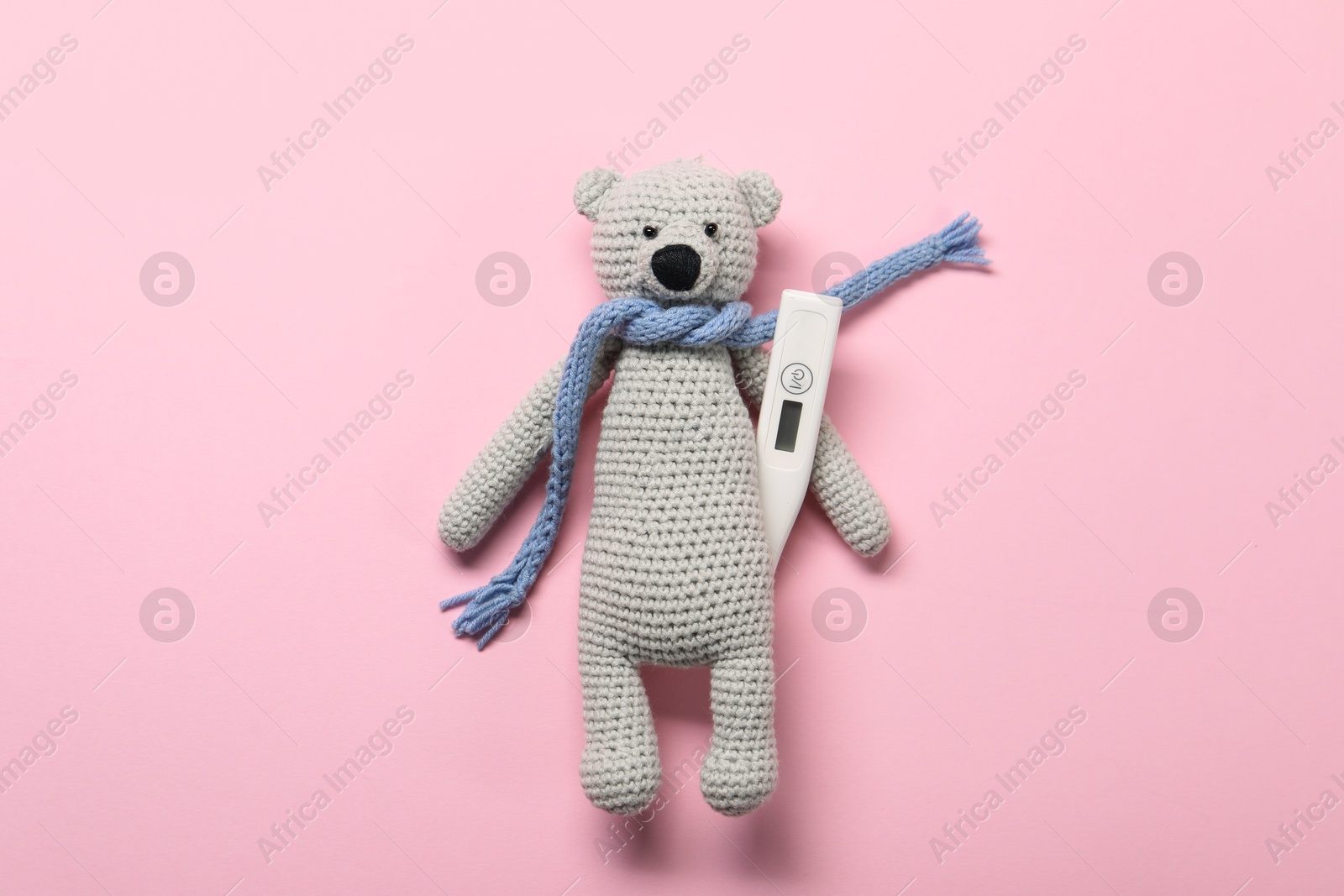 Photo of Toy bear and thermometer on pink background, top view