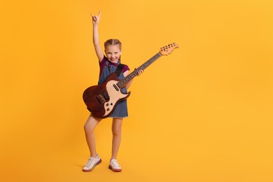 Photo of Cute girl with electric guitar on orange background