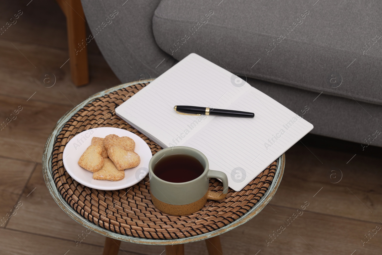 Photo of Cup of drink, cookies and notebook on coffee table indoors