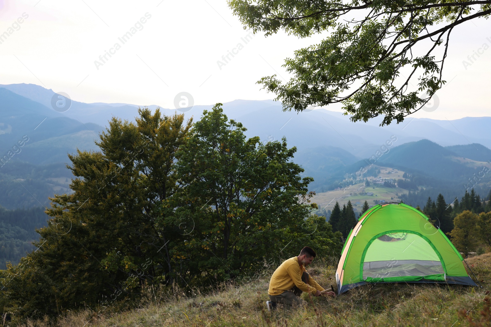 Photo of Man setting up camping tent in mountains