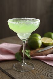 Delicious Margarita cocktail in glass on wooden table, closeup