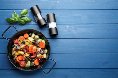 Pan with tasty cooked vegetables on blue wooden table, flat lay. Space for text