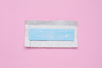 Photo of Unwrapped stick of tasty chewing gum on pink background, top view