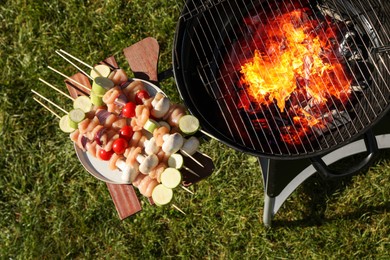 Photo of Skewers with meat and vegetables near barbecue grill outdoors, top view