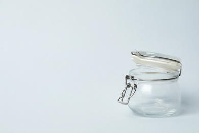 Photo of Open empty glass jar on light background, space for text