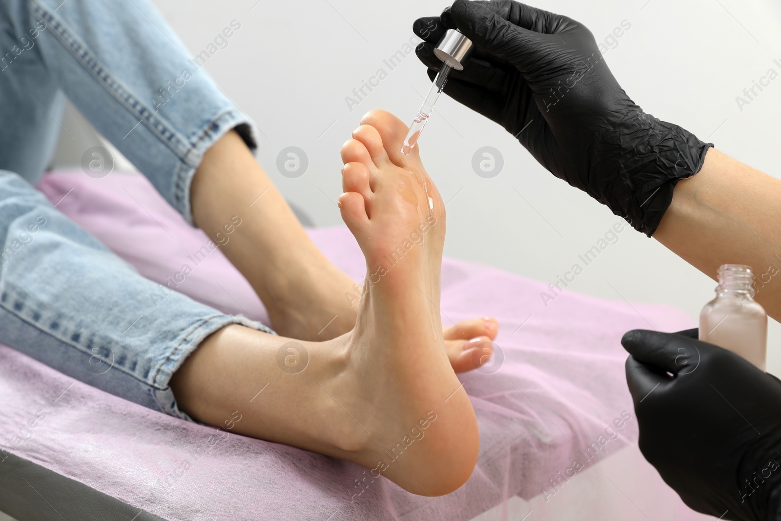 Photo of Professional master pouring oil on client's foot in beauty salon, closeup. Pedicure procedure