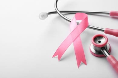 Photo of Pink ribbon and stethoscope on white background, space for text. Breast cancer concept