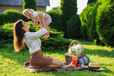 Photo of Mother and her baby daughter playing while having picnic in garden on sunny day