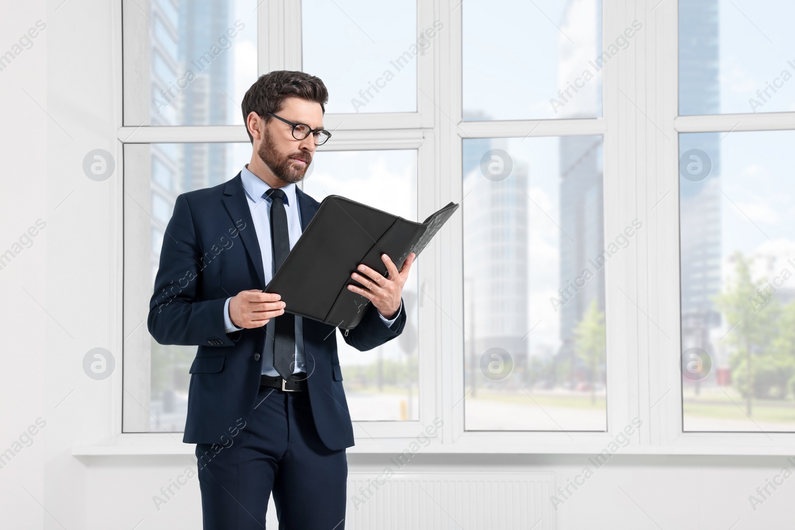 Photo of Handsome real estate agent with documents in empty room, space for text