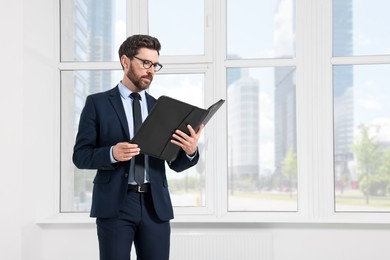 Photo of Handsome real estate agent with documents in empty room, space for text