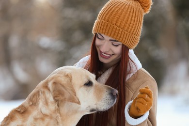 Photo of Beautiful young woman with adorable Labrador Retriever on winter day outdoors