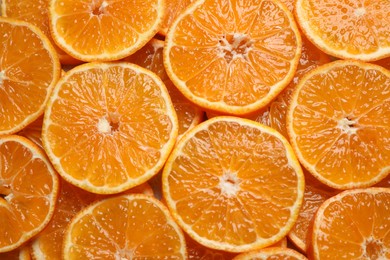 Slices of fresh ripe tangerines as background, top view. Citrus fruit