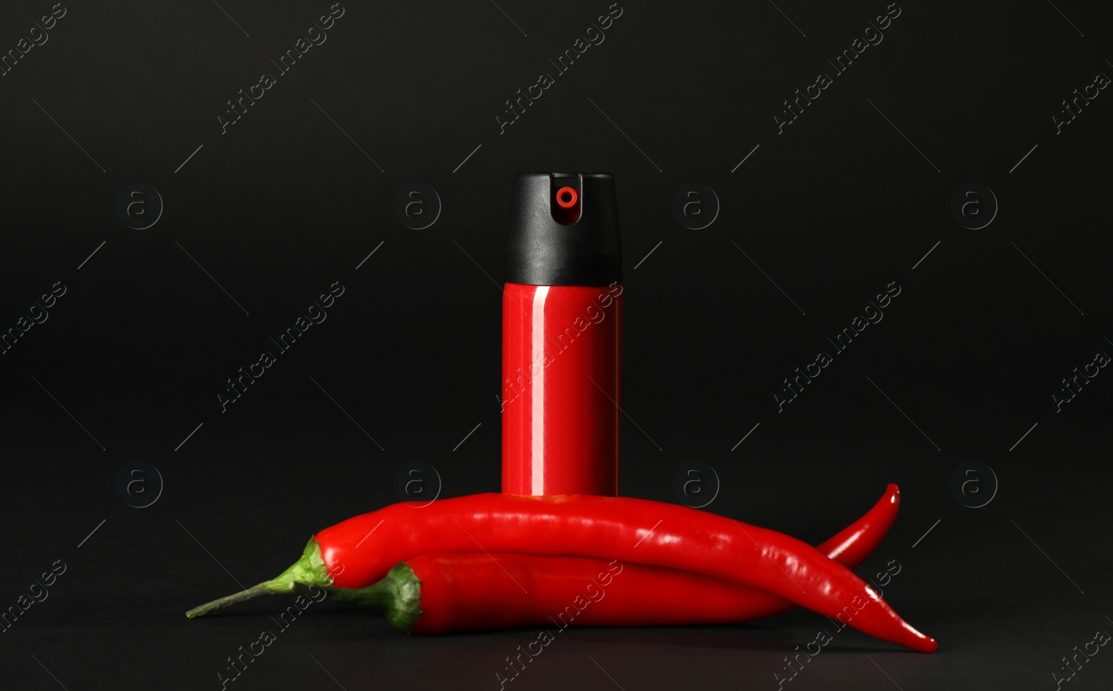 Photo of Bottle of gas pepper spray and fresh chili peppers on black background