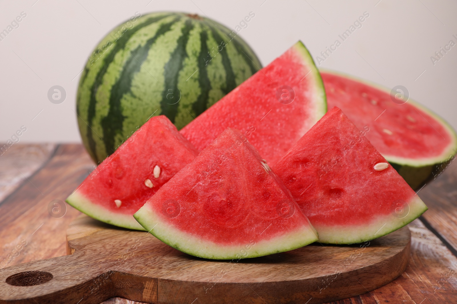 Photo of Juicy ripe cut and whole watermelons on wooden table, closeup